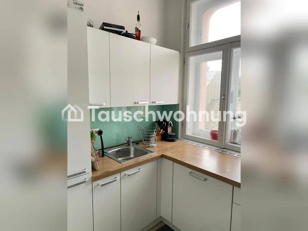 Helle Küche mit weißen Schränken, Holz-Arbeitsplatte und Fenster.