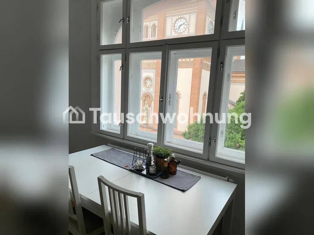 Essbereich mit weißem Tisch, Stühlen und Blick auf ein historisches Gebäude.