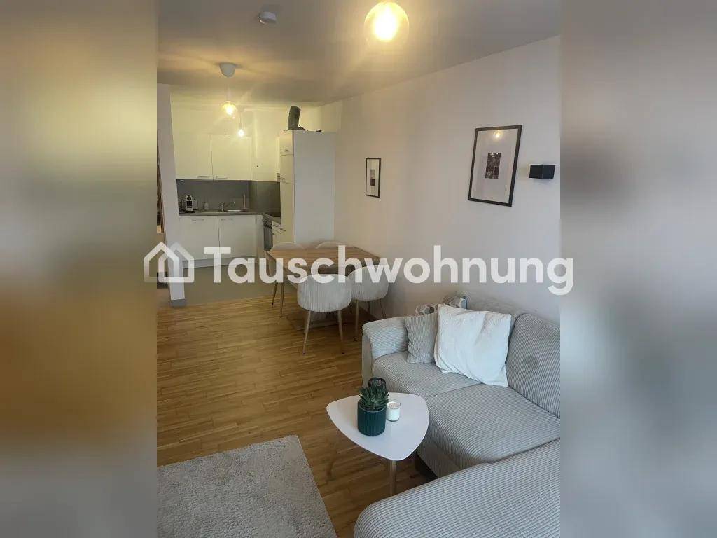 Offener Wohn- und Essbereich mit Holzboden und integrierter Küche im Hintergrund.