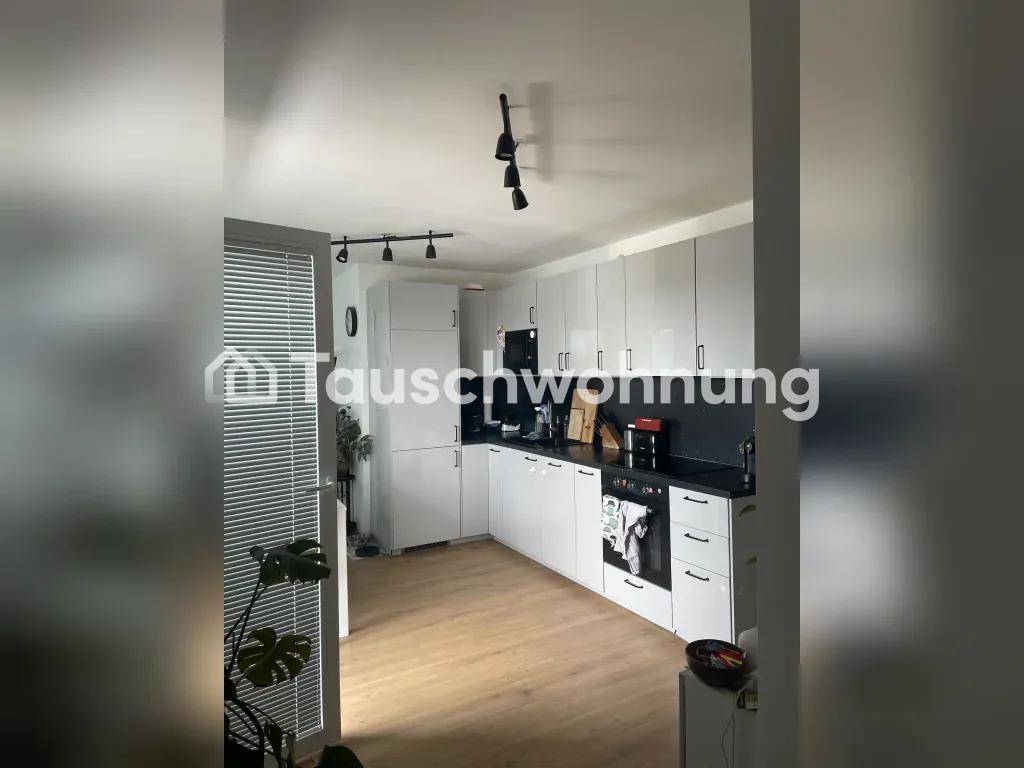 Moderne Küche mit grauen Hochglanzfronten, dunkler Arbeitsplatte und Laminatboden.