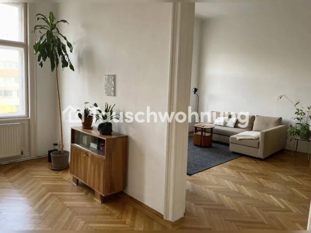 Heller Wohnbereich mit Fischgrätparkett, einem Sofa und einem dekorativen Holzschrank.