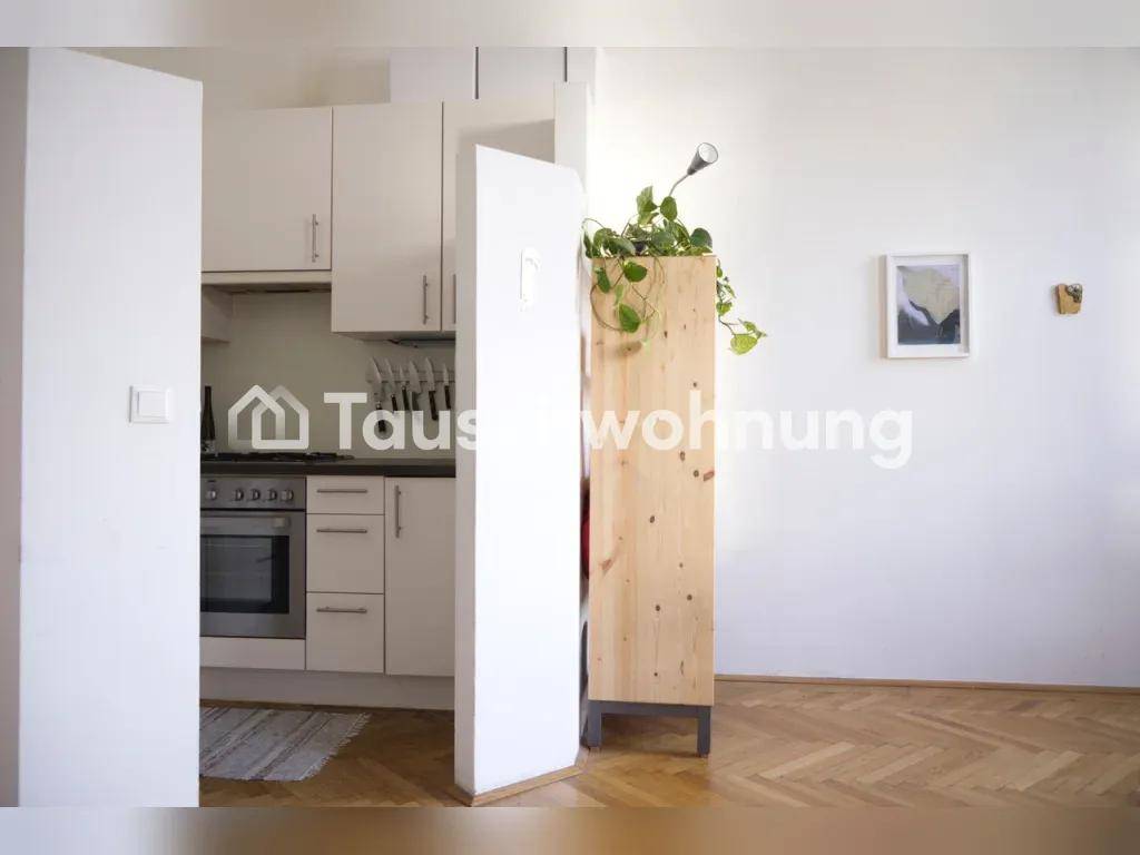 Moderne Küche mit weißen Schränken, integriertem Backofen und Holzboden.