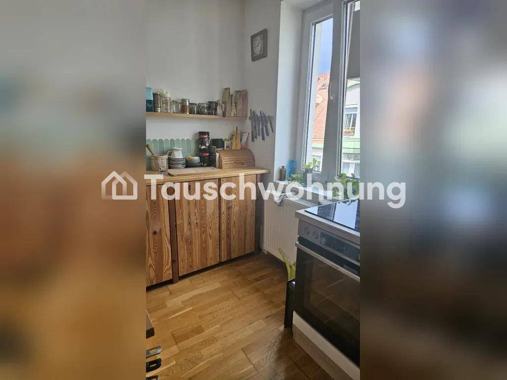 Helle Küche mit Fenster, Backofen und Holzschränken.