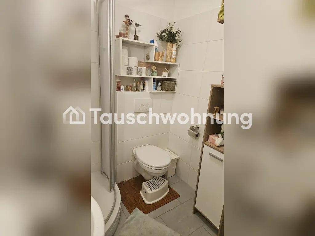 Badezimmer mit Duschkabine, Toilette und weißen Fliesen.
