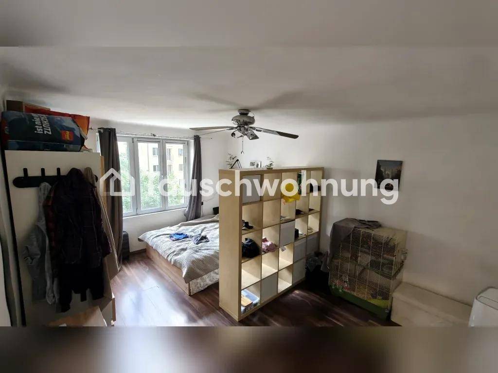Schlafbereich mit Bett, Regal als Raumteiler und Fenster mit Blick nach draußen.