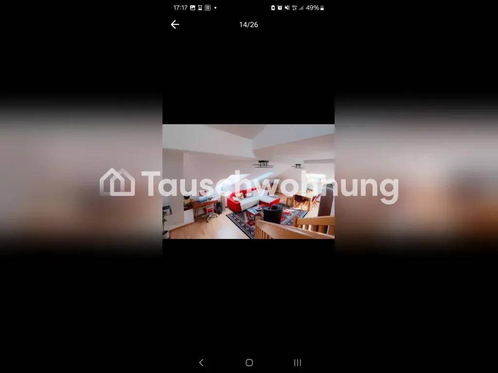 Helles Wohnzimmer mit rotem Sofa, Teppich und sichtbarer Holztreppe unter einer Dachschräge.