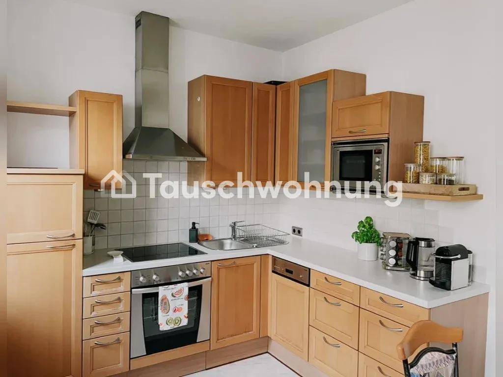 Funktionale Küche mit Holzschränken, weißen Arbeitsplatten, Herd, Backofen und Mikrowelle.