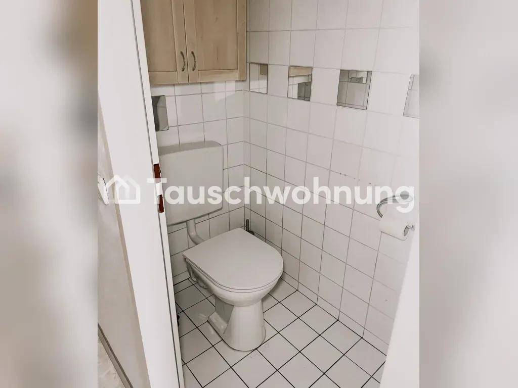 Kleines Gäste-WC mit weiß gefliesten Wänden, Toilette und einem praktischen Hängeschrank.