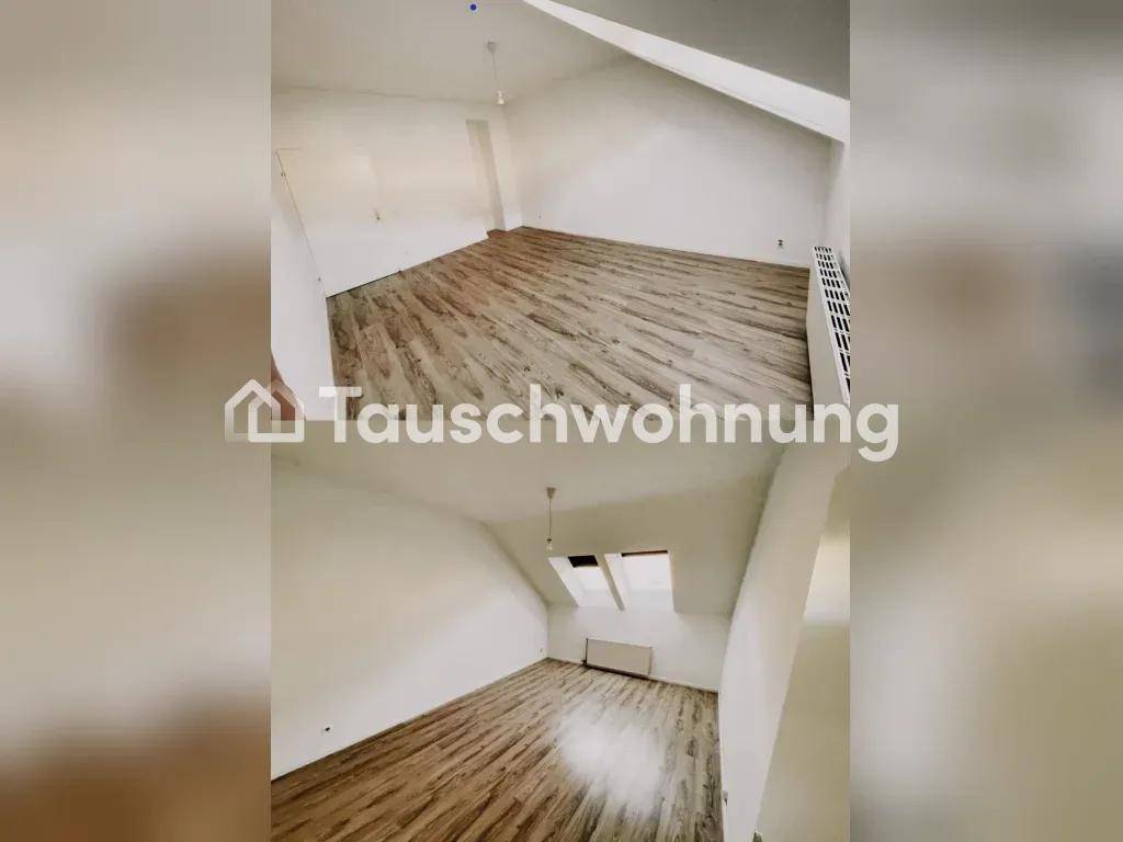 Leerer Raum im Dachgeschoss mit schrägen Wänden, Holzboden und einem Dachfenster für natürliches Licht.