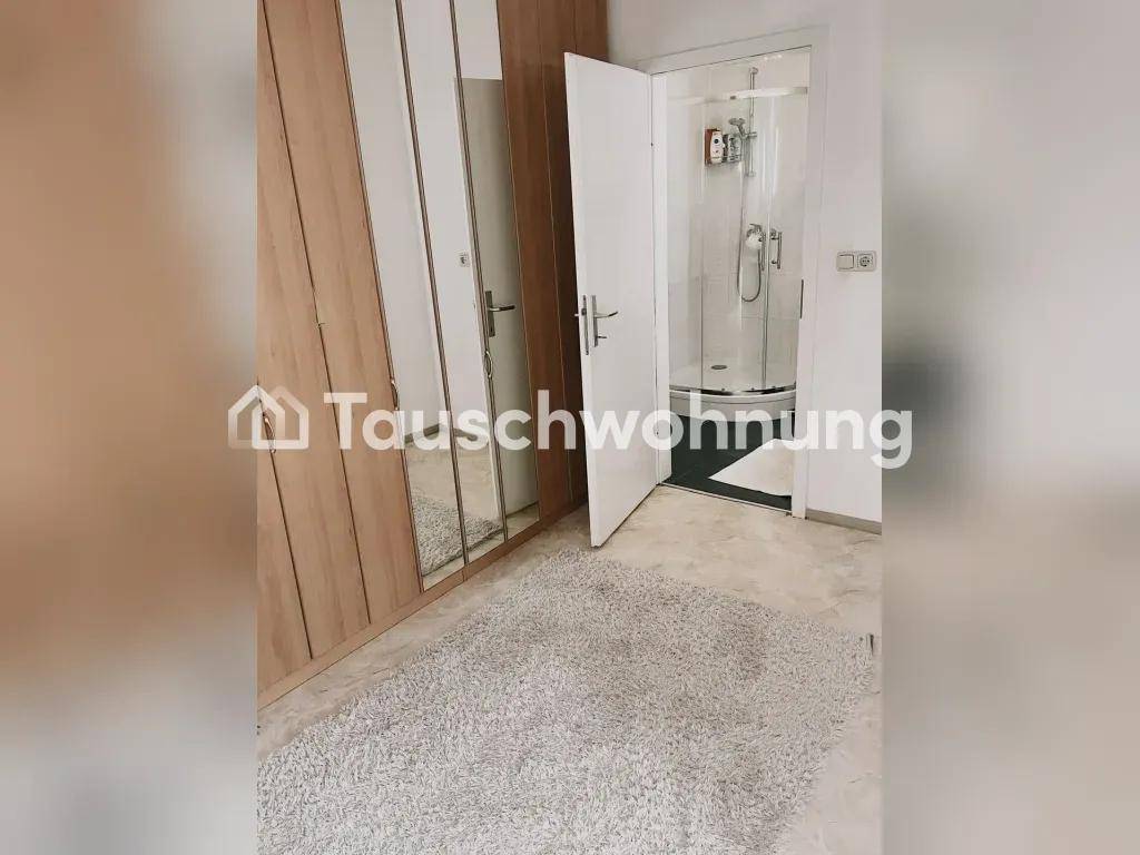 Raum mit großem Holzschrank und Spiegeltüren, daneben eine offene Tür zu einer Duschkabine.