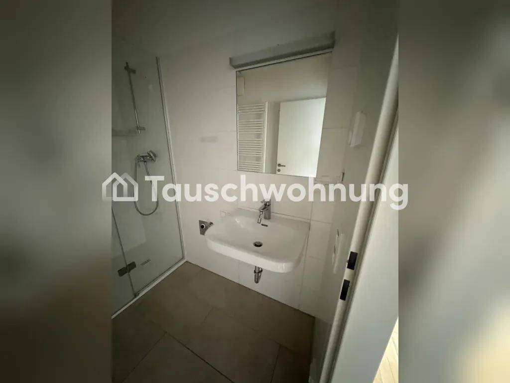 Kleines Badezimmer mit Duschkabine, Waschbecken, Spiegel und beheiztem Handtuchhalter, auf beigefarbenen Fliesen.