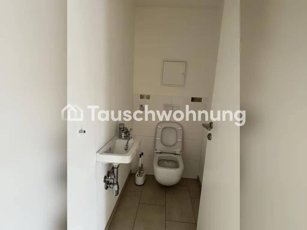 Kleines Gäste-WC mit Toilette und Handwaschbecken, auf beigefarbenen Fliesen.