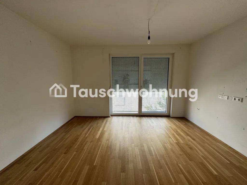 Geräumiger, leerer Raum mit hellem Holzfußboden und großer Fensterfront mit Rollläden.