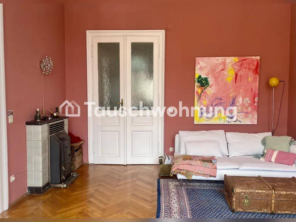 Wohnzimmer mit rosa Wänden, Fischgrätparkett und einem traditionellen Kachelofen.