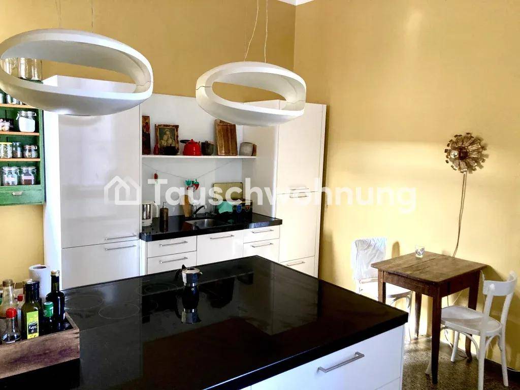 Helle Küche mit Kücheninsel, weißen Schränken und einem kleinen Essbereich.
