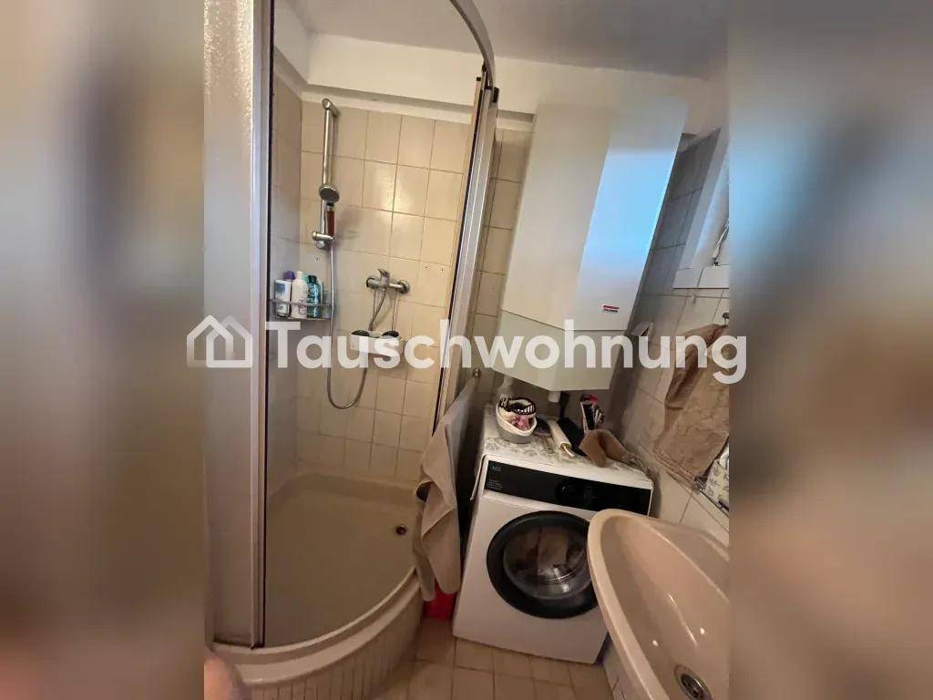 Badezimmer mit Duschkabine, Waschmaschine und einem Waschbecken.