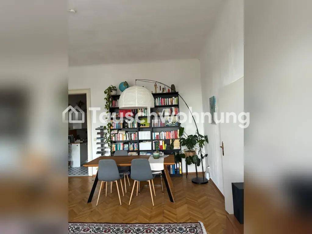 Essbereich mit großem Bücherregal, Holztisch und Pendelleuchte, Teil eines offenen Wohnkonzepts.