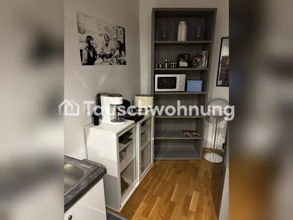 Offener Wohnbereich mit Kaffeemaschine, Mikrowelle auf einem Regal und Holzboden.