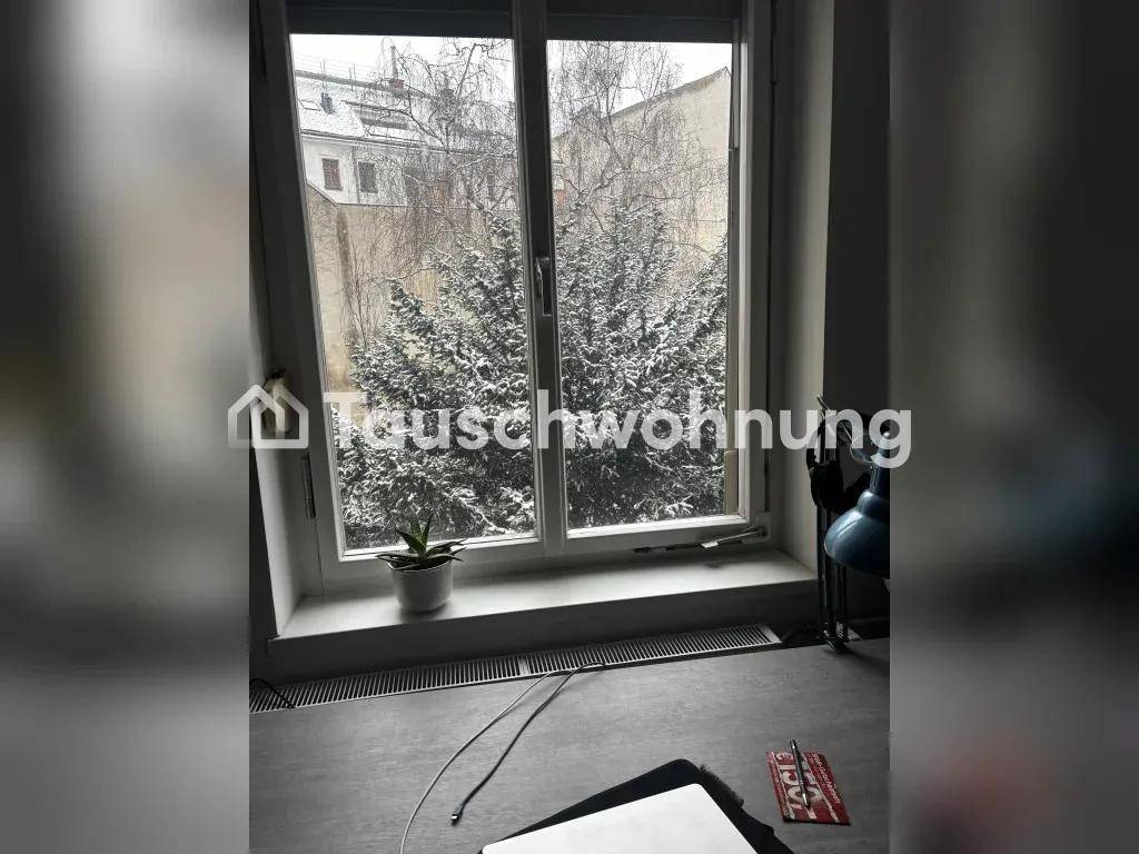 Fensterblick auf schneebedeckte Bäume und Gebäude im Hintergrund, von einem Innenraum aus.