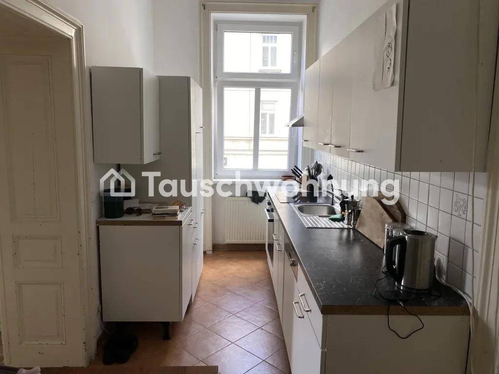 Funktionale Küche mit weißen Schränken, dunkler Arbeitsplatte und Fenster mit Blick nach draußen.
