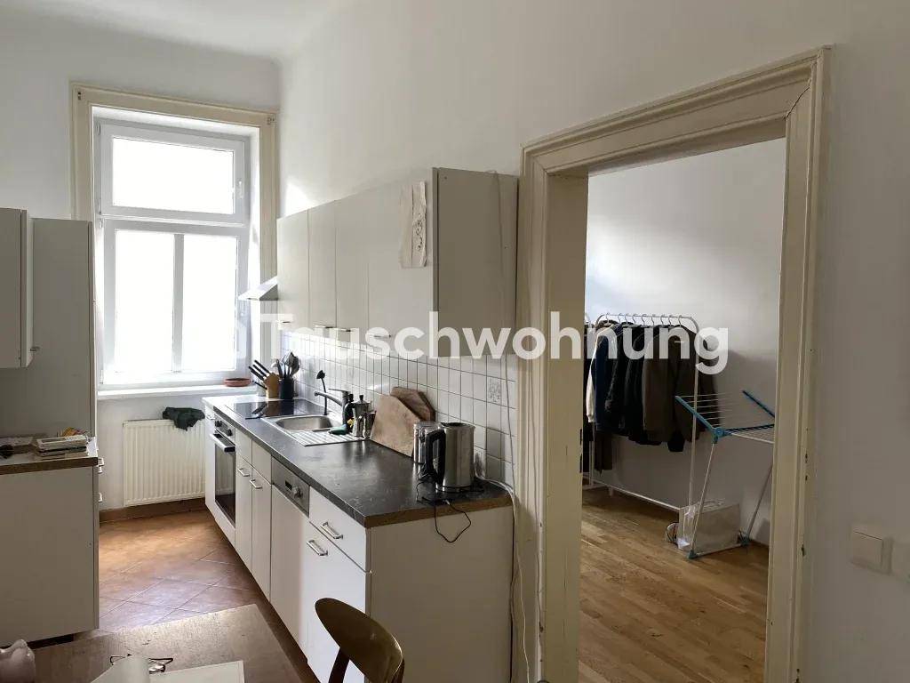 Helle Küche mit weißen Einbauschränken und Fliesenboden, mit Zugang zu einem weiteren Raum.