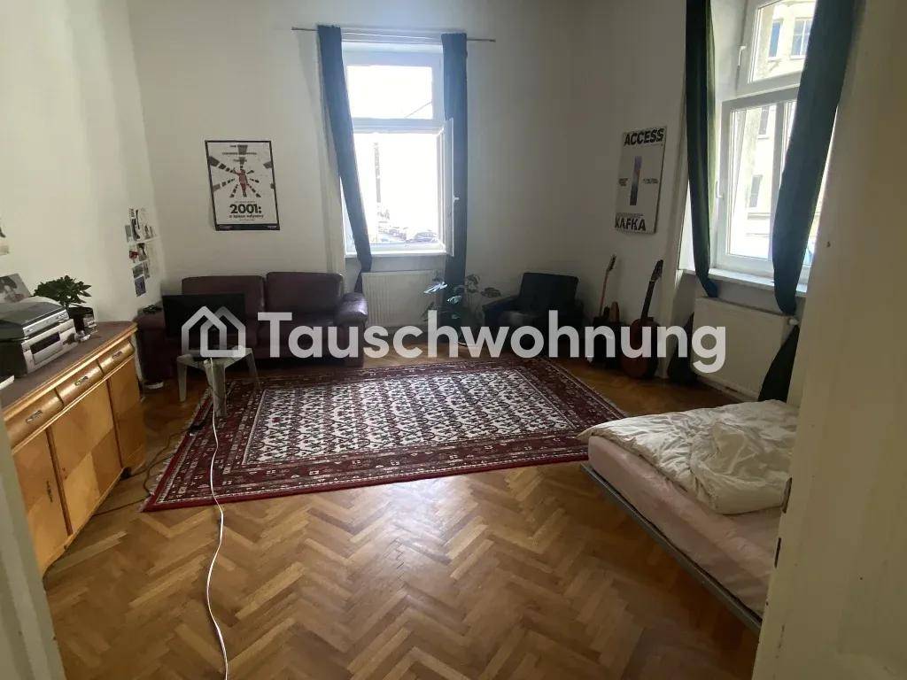 Gemütliches Wohnzimmer mit Fischgrätparkett, Sofa und Teppich, gut beleuchtet durch große Fenster.