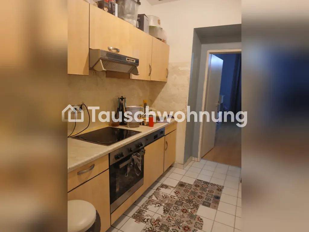 Küche mit hellen Holzschränken, Einbauherd und gemusterten Bodenfliesen.