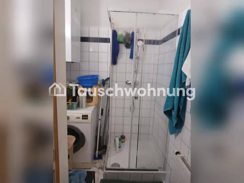 Badezimmer mit Duschkabine, Waschmaschine und weißen Wandfliesen.