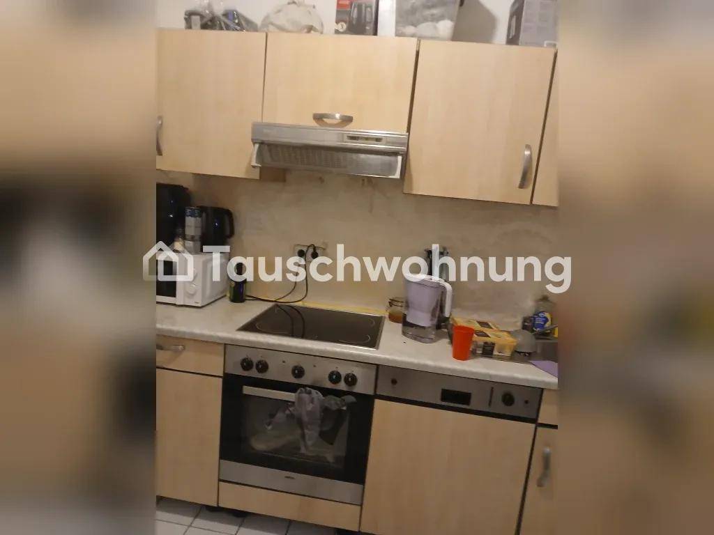 Funktionale Küche mit hellen Holzschränken, Einbaugeräten und einer Dunstabzugshaube.
