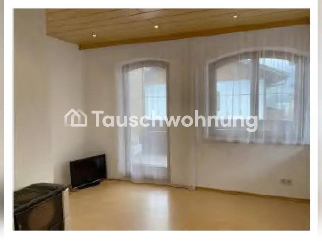 Geräumiger Wohnbereich mit Laminatboden, Holzbalkendecke und Zugang zu einem Balkon.