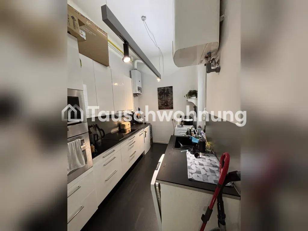 Moderne Küche mit weißen Hochglanzschränken, dunklen Arbeitsplatten und integrierten Geräten für effizientes Kochen.