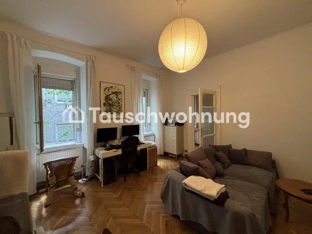 Gemütliches Wohnzimmer mit Sofa, Schreibtisch und klassischem Fischgrätparkettboden, hell durch Tageslicht.