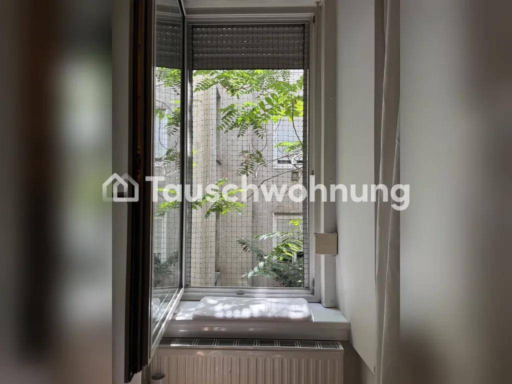 Fenster mit Blick auf einen begrünten Innenhof, das viel Tageslicht in den Raum lässt.