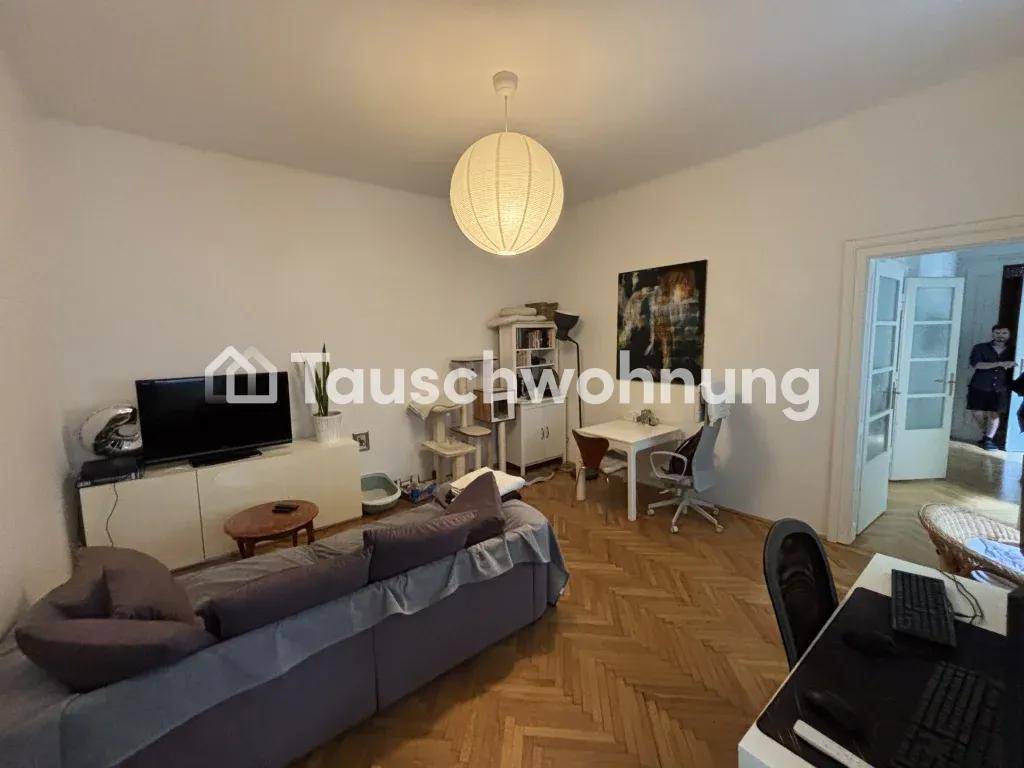 Wohnzimmer mit Fernseher, kleinem Esstisch und einem Katzenbaum, funktional und wohnlich eingerichtet.