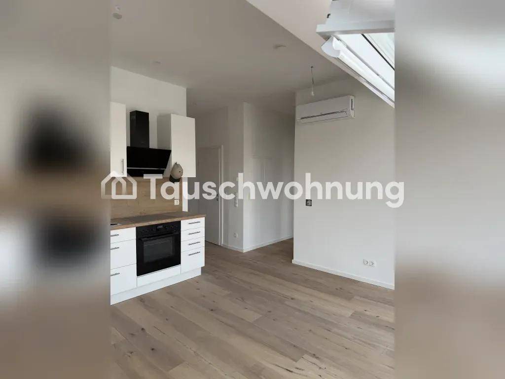 Leere Küche mit weißen Einbauschränken, Backofen, Dunstabzugshaube und Klimaanlage.