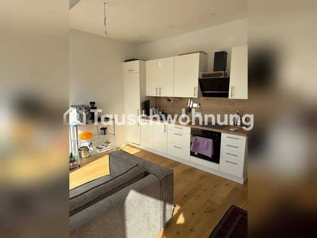 Moderne Einbauküche mit weißen Schränken, Holzarbeitsplatte und offener Gestaltung zum Wohnbereich.