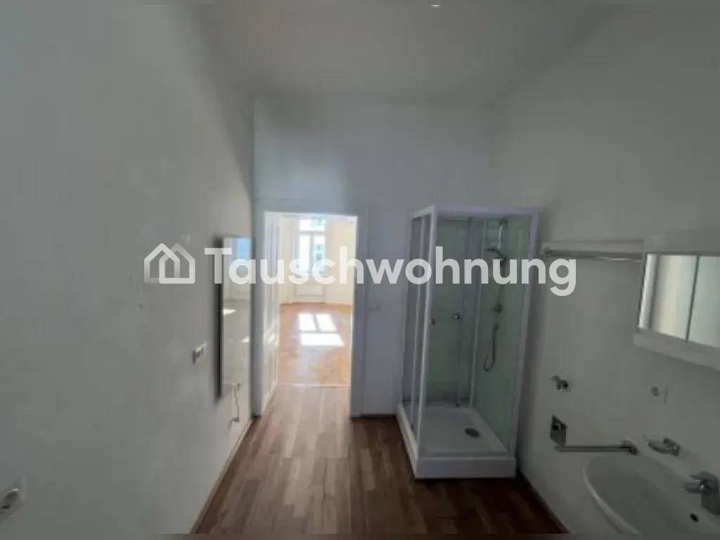 Langer Raum mit Duschkabine und Waschbecken, der zu einem weiteren Zimmer führt.
