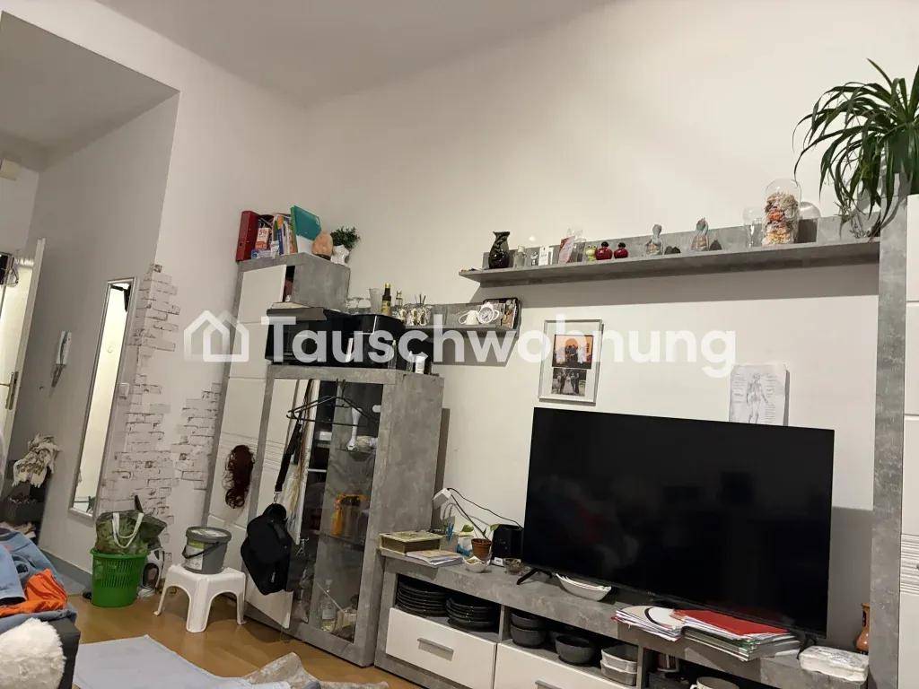 Wohnzimmer mit Fernseher, Medienschrank und Regalen, dekoriert mit Pflanzen und persönlichen Gegenständen.