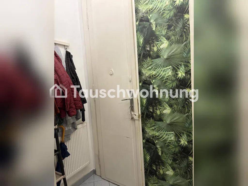 Eingangsbereich mit Garderobe, Heizkörper und einer Tür mit tropischem Blattmuster.