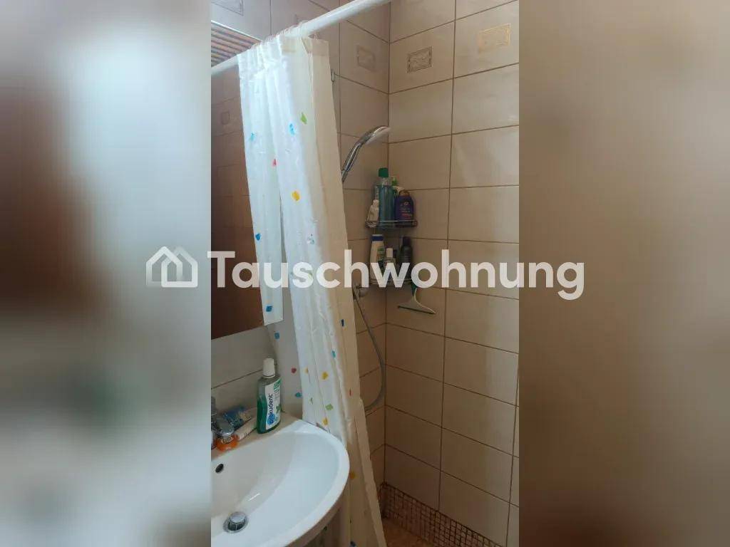 Badezimmer mit Duschbereich, Vorhang und Waschbecken, gefliest in hellen Farbtönen.