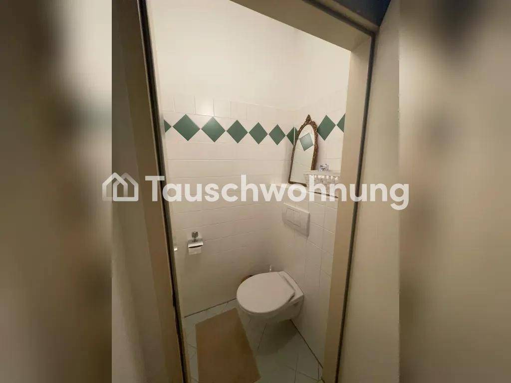 Kleines Gäste-WC mit weißen Fliesen und einer dekorativen grünen Bordüre an den Wänden.