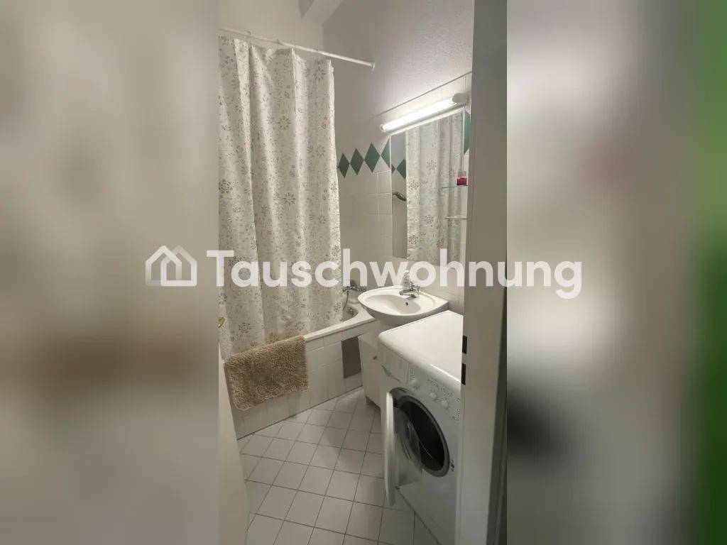 Badezimmer mit Badewanne, Waschbecken und Waschmaschine, gefliest in Weiß und Grün.