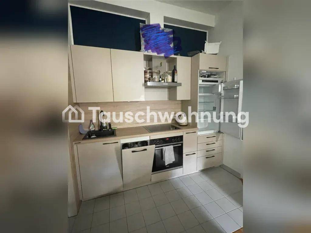Kleine Einbauküche mit hellen Schränken, integrierten Geräten und Fliesenboden in einem kompakten Raum.