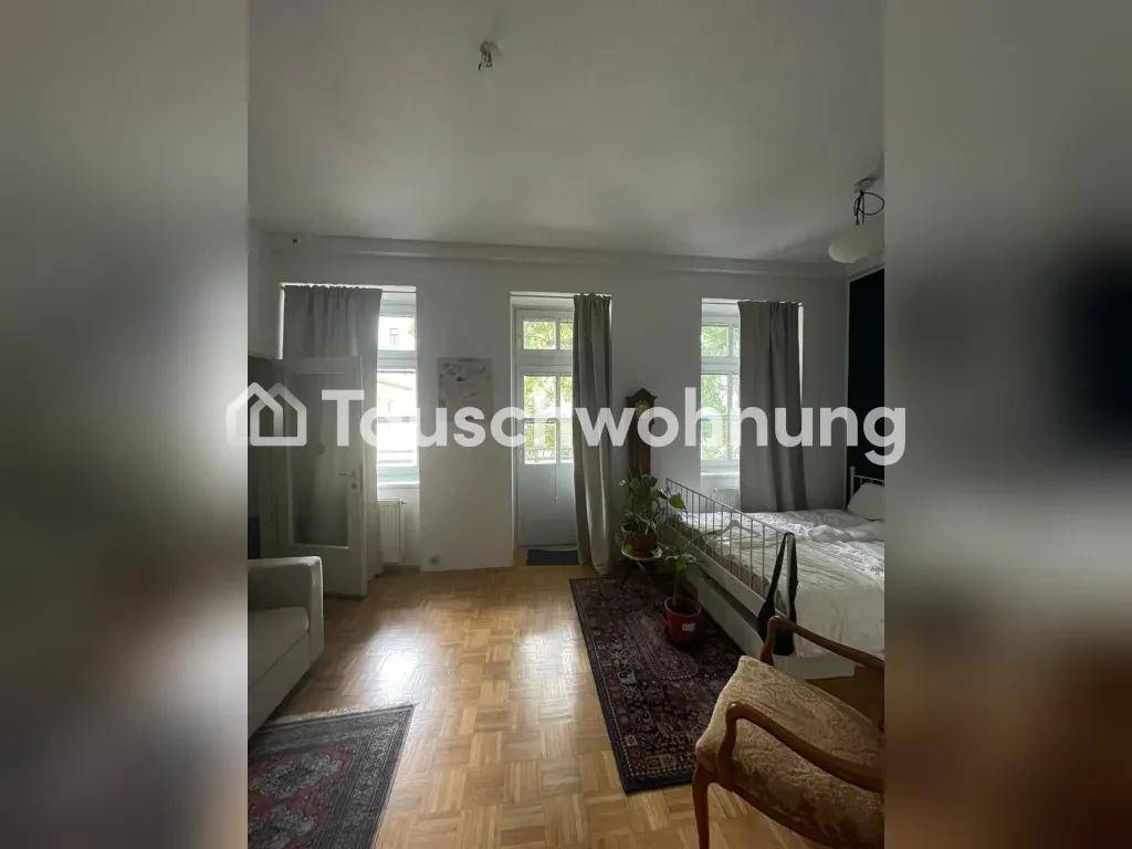 Heller Wohnbereich mit Parkettboden, hohen Fenstern und Zugang zu einem Außenbereich.