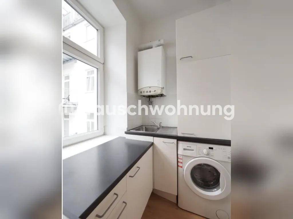 Küchenbereich mit Spüle, Waschmaschine und Gastherme unter einem Fenster.