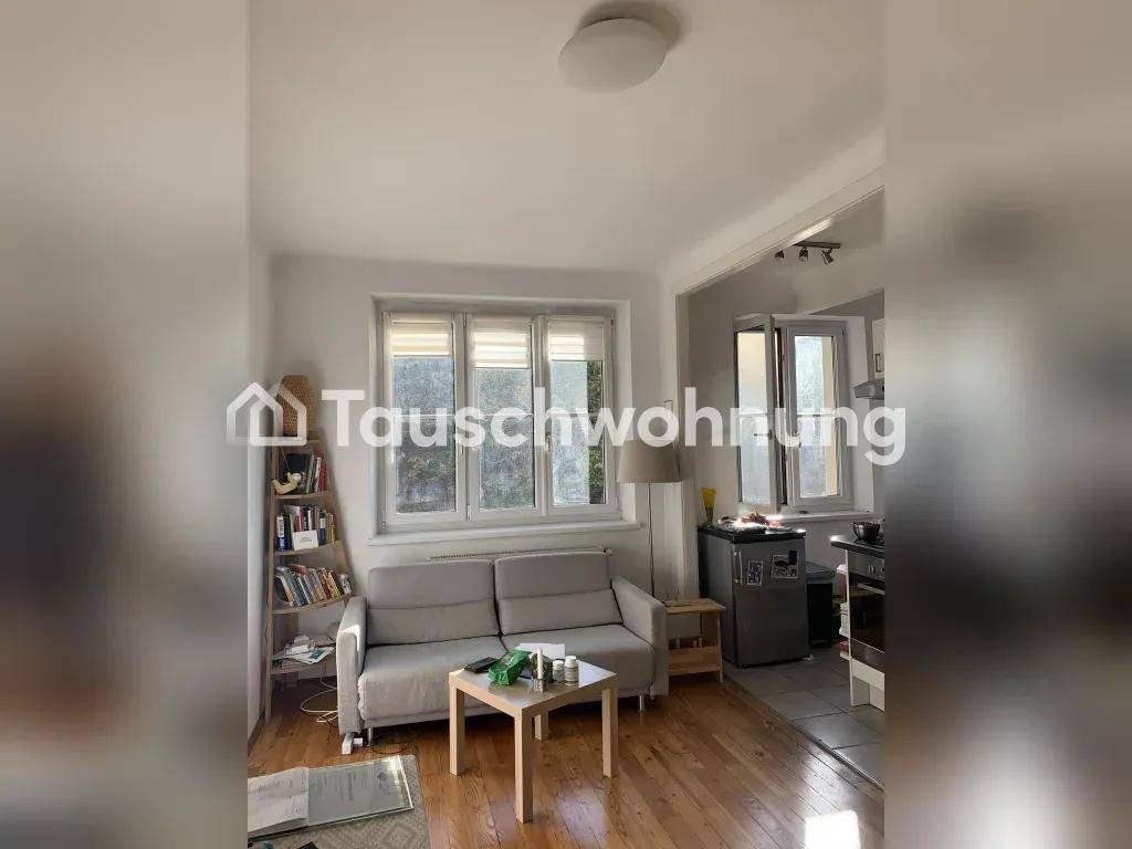Gemütlicher Wohnbereich mit Sofa, Holzboden und offener Verbindung zu einer semi-offenen Küche.