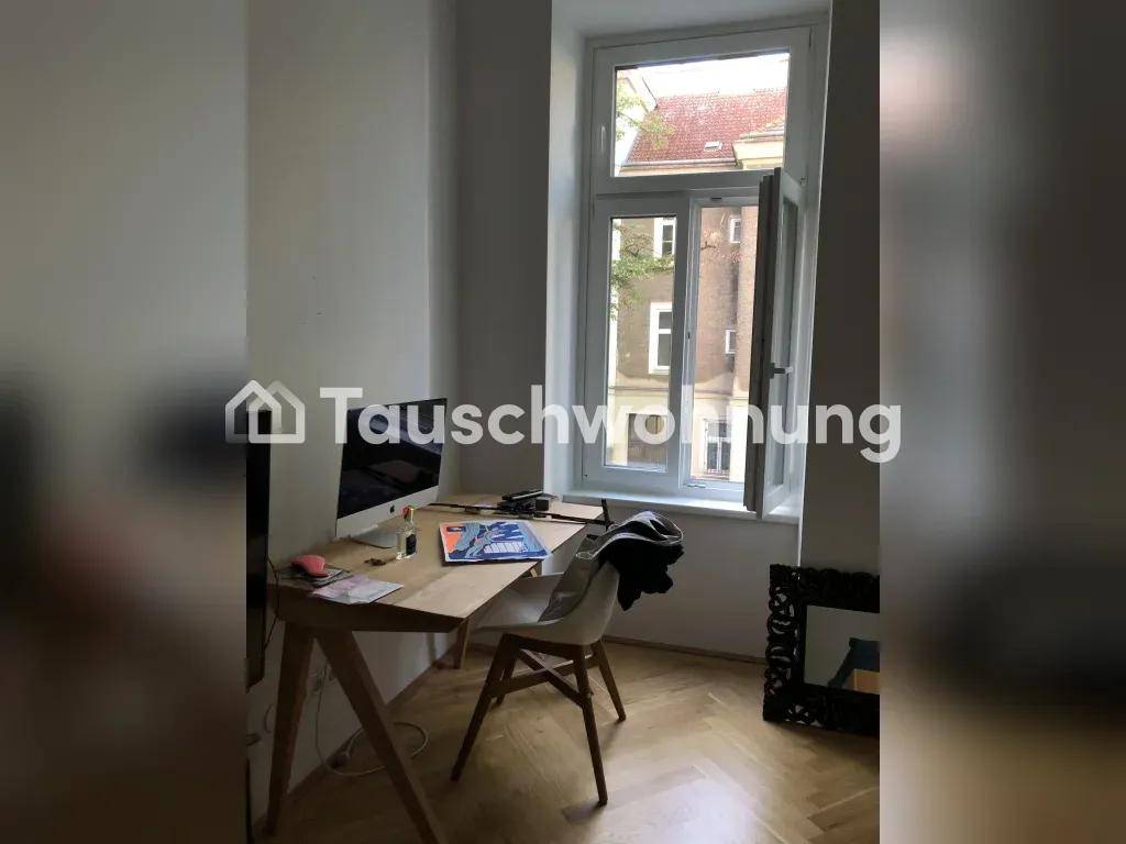Arbeitsbereich mit Schreibtisch, Computer und Parkettboden, gut beleuchtet durch ein großes Fenster.