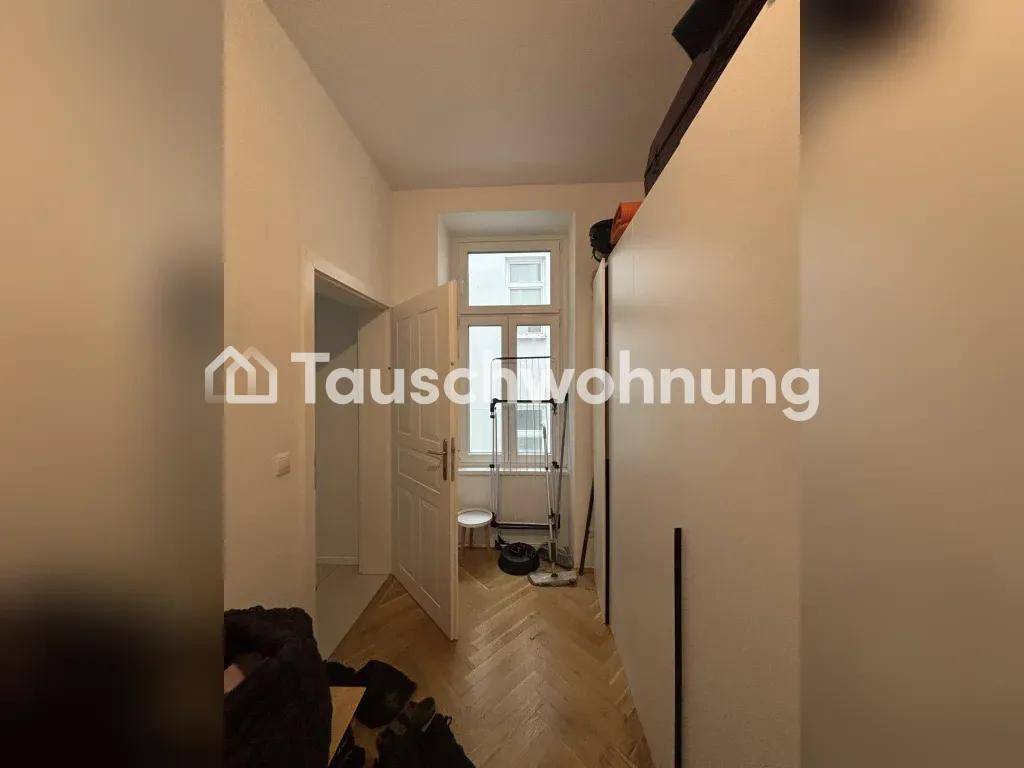 Schmaler Flur oder Durchgangsbereich mit Parkettboden und einem Fenster am Ende, führt zu einem weiteren Raum.