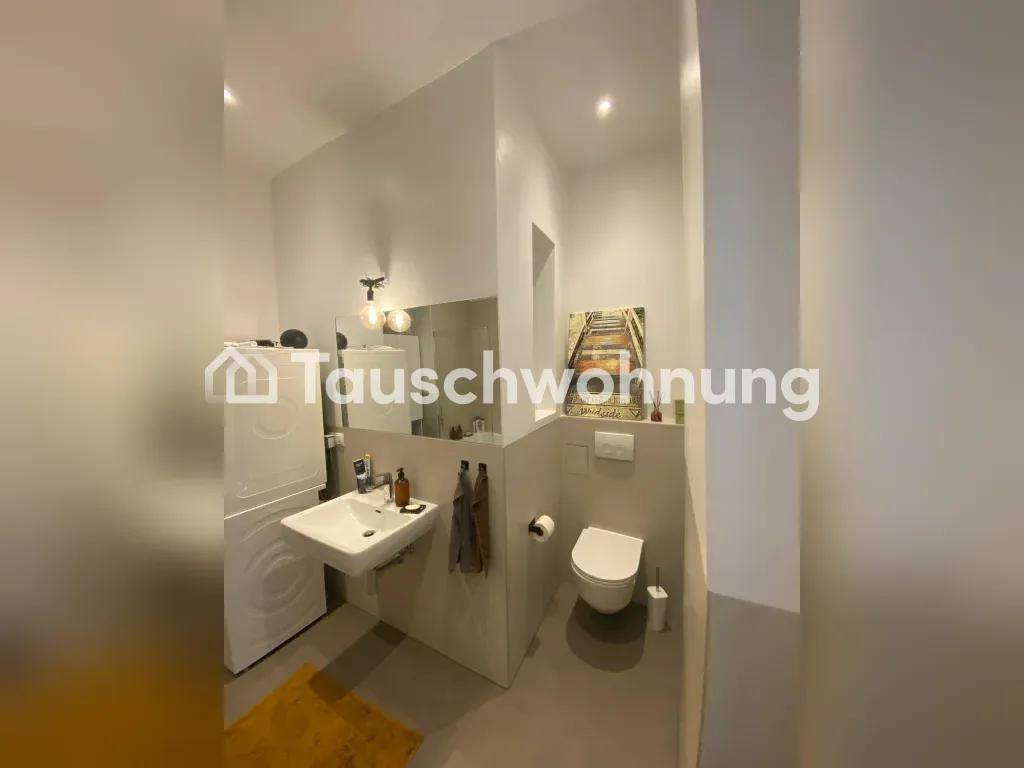 Modernes Badezimmer mit Waschbecken, Toilette und Waschmaschine, in hellen Farbtönen gehalten.
