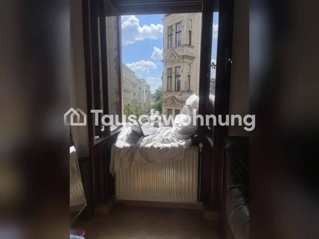 Blick aus einem geöffneten Fenster auf eine belebte Straße mit historischen Gebäuden und Bäumen.